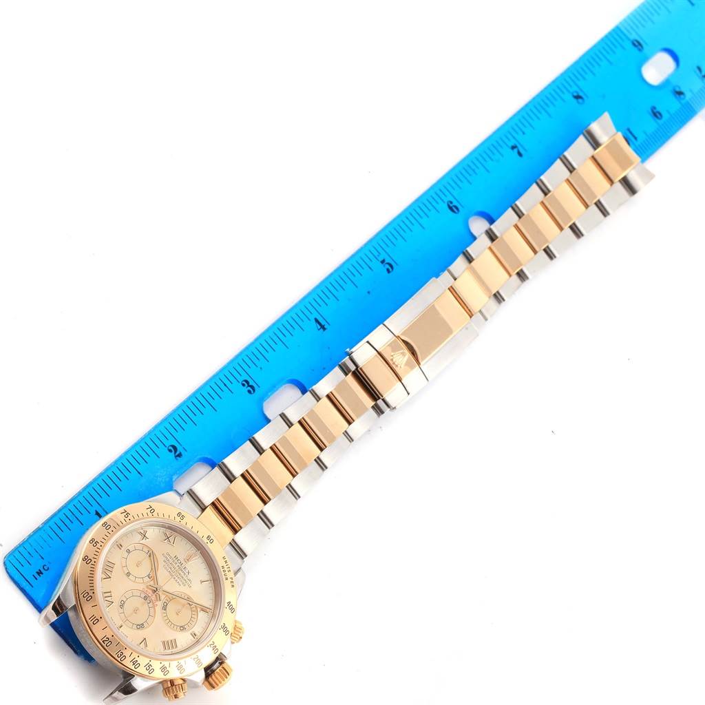 The image shows a Rolex Daytona 116523 Men's Steel and Gold (two tone) Mother of Pearl Dial 116523 Men's Steel and Gold (two tone) Mother of Pearl Dial watch placed next to a ruler, highlighting the watch face and the entire bracelet.