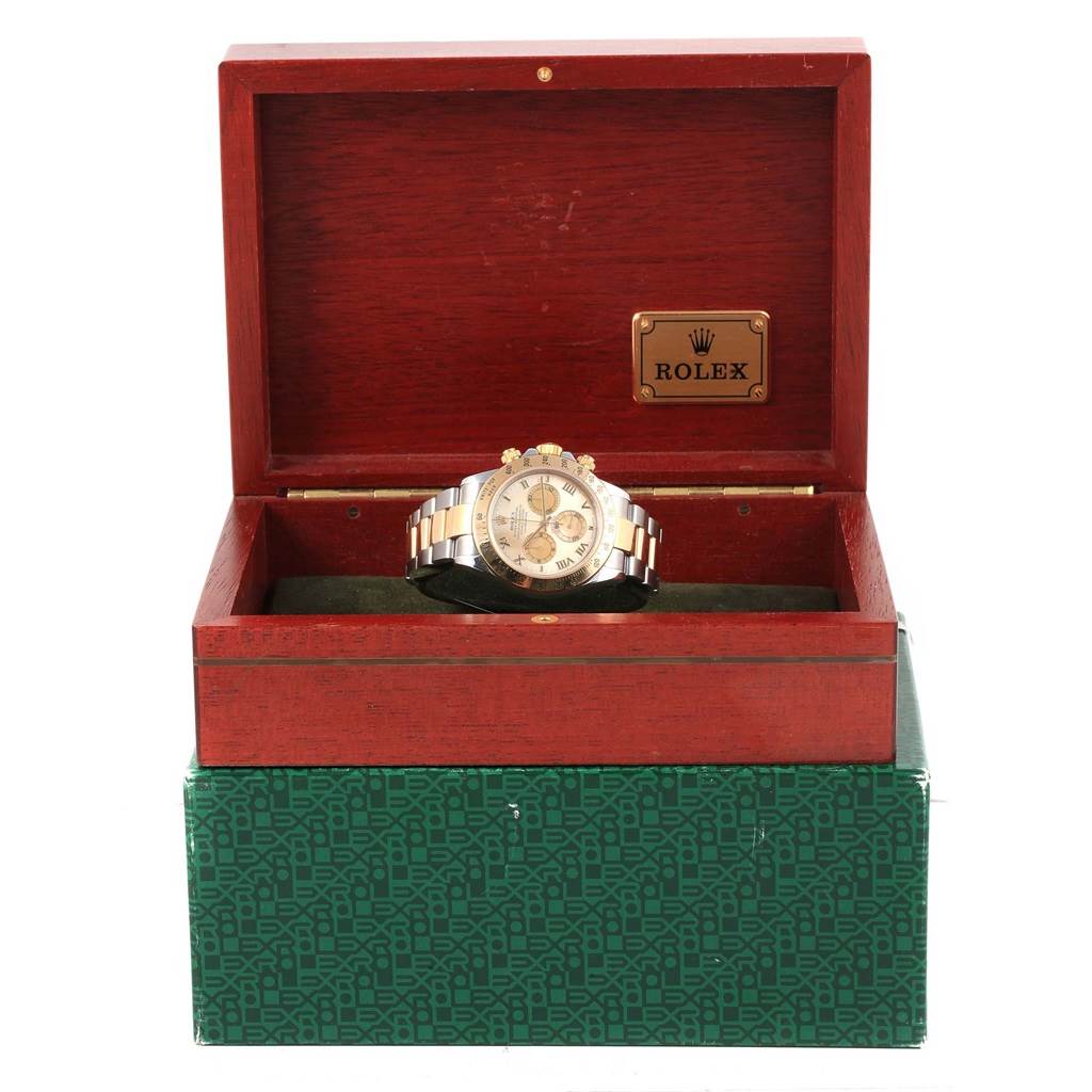 The Rolex Daytona 116523 Men's Steel and Gold (two tone) Mother of Pearl Dial 116523 Men's Steel and Gold (two tone) Mother of Pearl Dial watch is pictured head-on, displayed inside an open wooden box with a green patterned base.