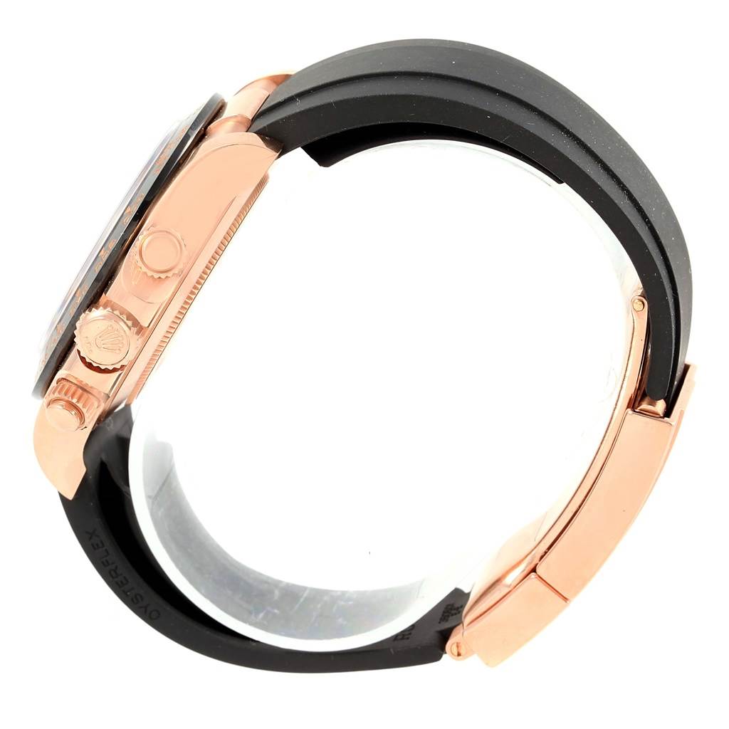 The image shows a side view of a Rolex Daytona 116515 Men's Rose Gold Brown Dial 116515 Men's Rose Gold Brown Dial watch, focusing on the crown, chronograph pushers, and black strap.