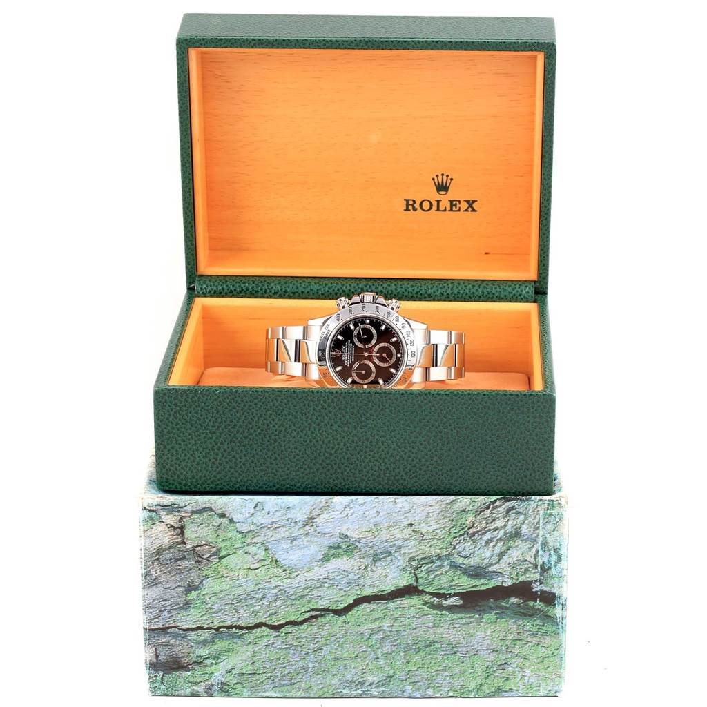 The Rolex Daytona 116520 Men's Stainless Steel Black Dial 116520 Men's Stainless Steel Black Dial watch is shown front-facing, displayed in an open green and wood-tone Rolex box.