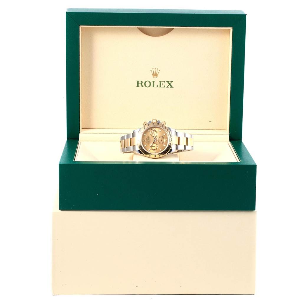 The Rolex Daytona 116523 Men's Steel and Gold (two tone) Champagne Dial 116523 Men's Steel and Gold (two tone) Champagne Dial watch is shown front-facing inside its open green and beige branded box.