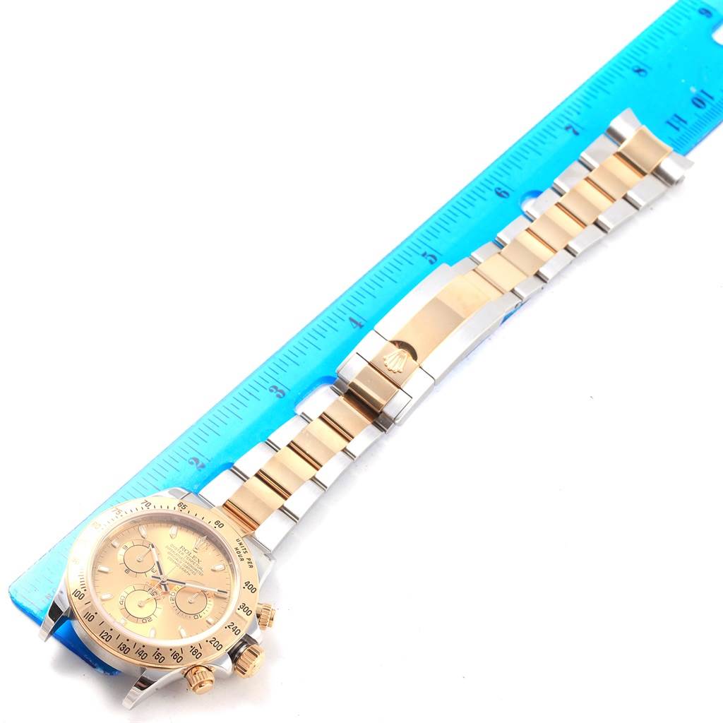 The image shows a Rolex Daytona 116523 Men's Steel and Gold (two tone) Champagne Dial 116523 Men's Steel and Gold (two tone) Champagne Dial watch laying flat with its bracelet extended, measured against a blue ruler.