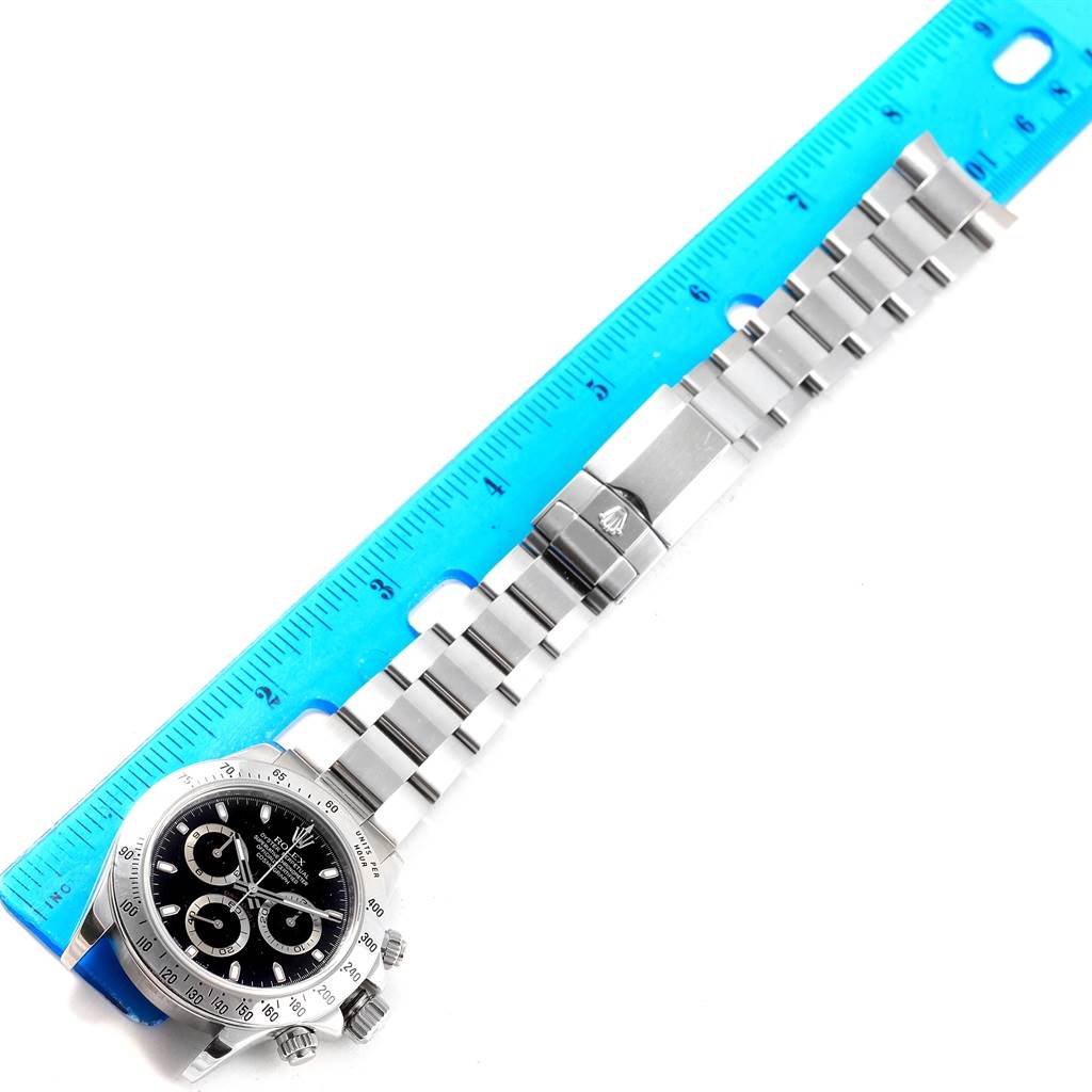 The image shows a Rolex Daytona 116520 Men's Stainless Steel Black Dial 116520 Men's Stainless Steel Black Dial watch laid flat next to a ruler, displaying the face, bezel, and metal bracelet.