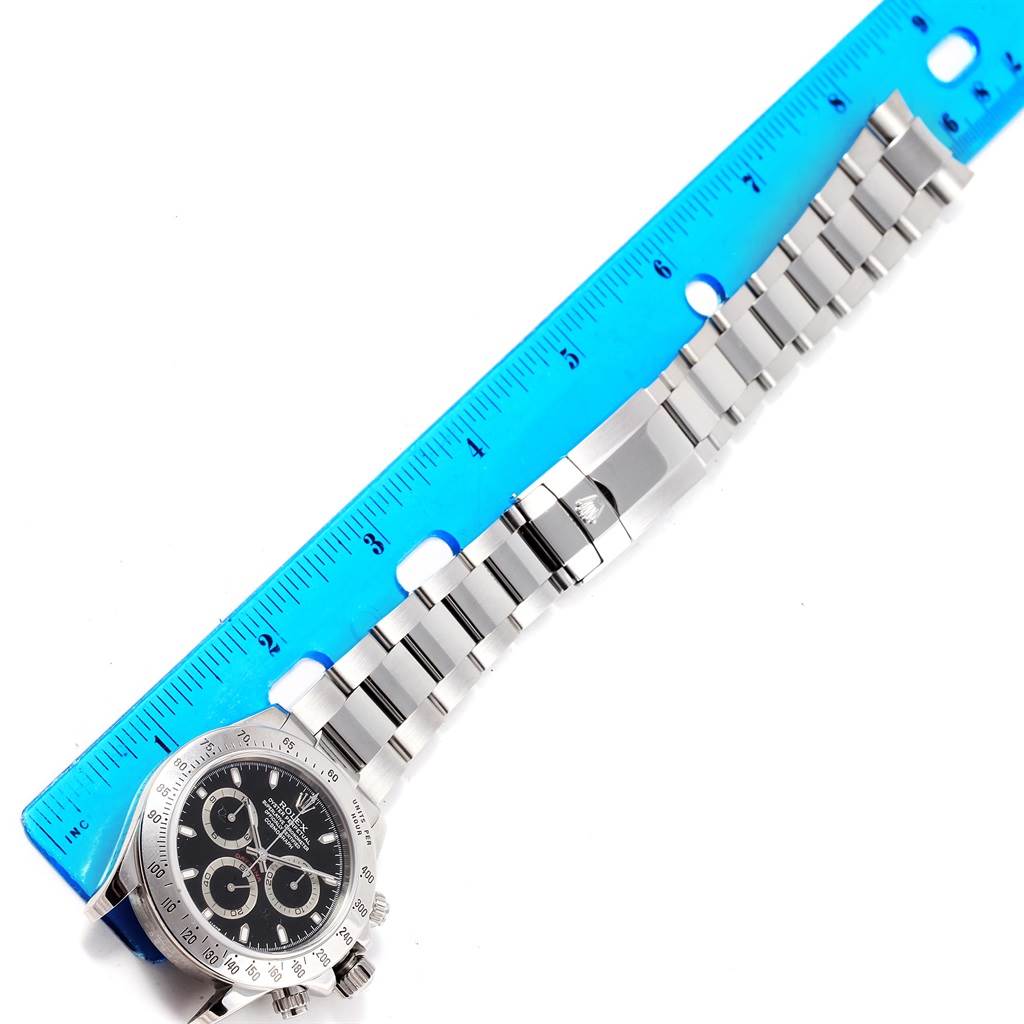 The image shows a Rolex Daytona 116520 Men's Stainless Steel Black Dial 116520 Men's Stainless Steel Black Dial watch with a bracelet clasp and a blue ruler for scale.