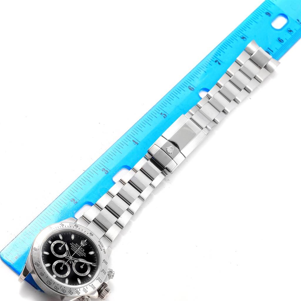 The image shows the top view of a Rolex Daytona 116520 Men's Stainless Steel Black Dial 116520 Men's Stainless Steel Black Dial watch, highlighting its face and metal bracelet laid next to a ruler.