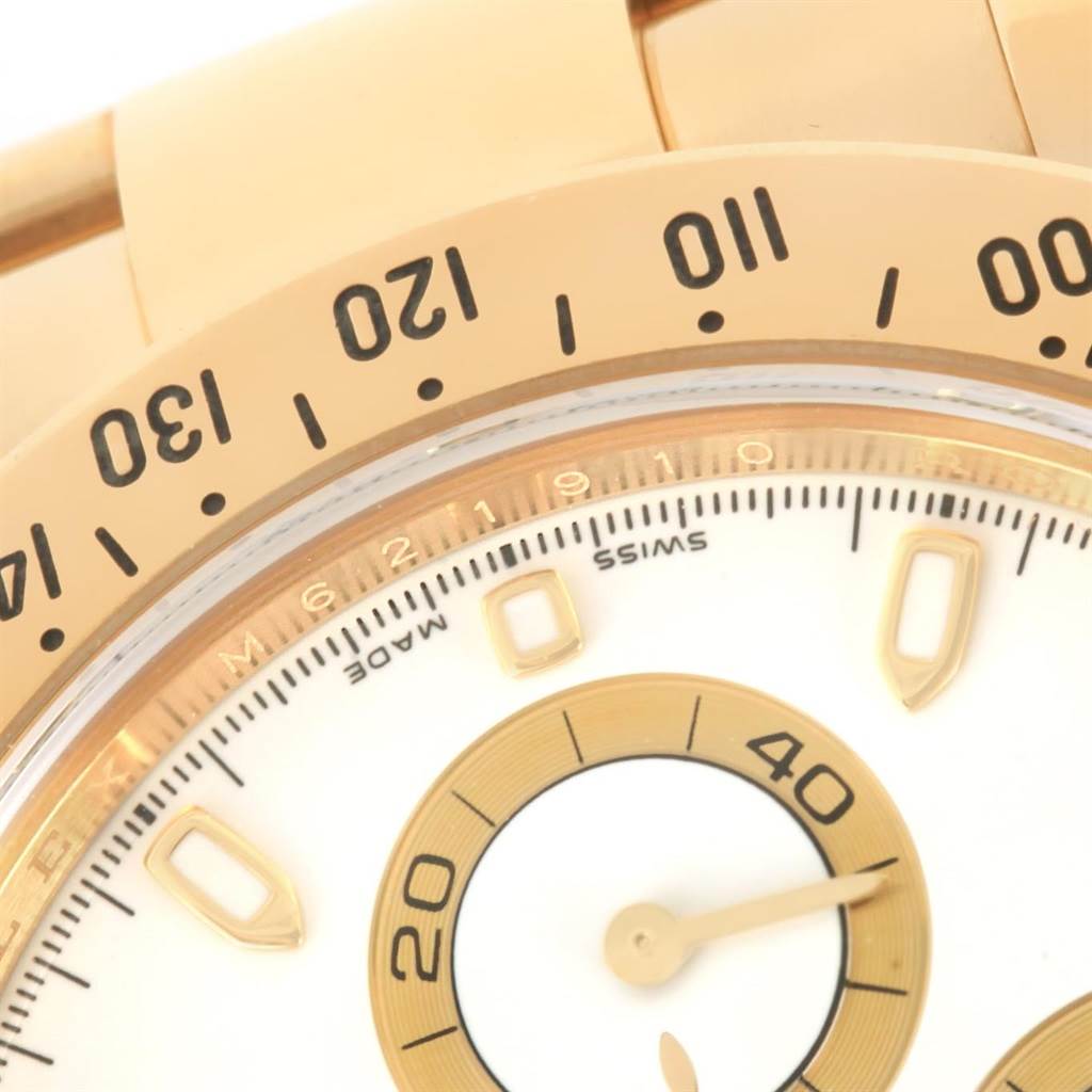 This close-up image shows the bezel and part of the dial of a Rolex Daytona 116528 Men's Yellow Gold White Dial 116528 Men's Yellow Gold White Dial watch.