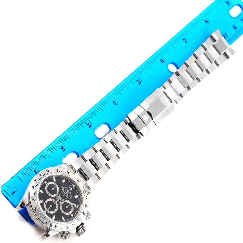 The image shows a top view of a Rolex Daytona 116520 Men's Stainless Steel Black Dial 116520 Men's Stainless Steel Black Dial watch, highlighting its face, bezel, and metal bracelet, with a ruler for scale.