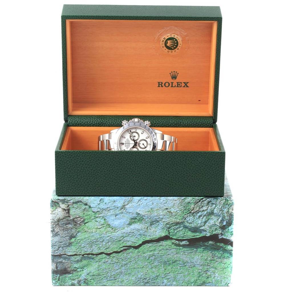 The Rolex Daytona 116520 Men's Stainless Steel White Dial 116520 Men's Stainless Steel White Dial watch is displayed front-on inside an open, luxurious green and wood box.