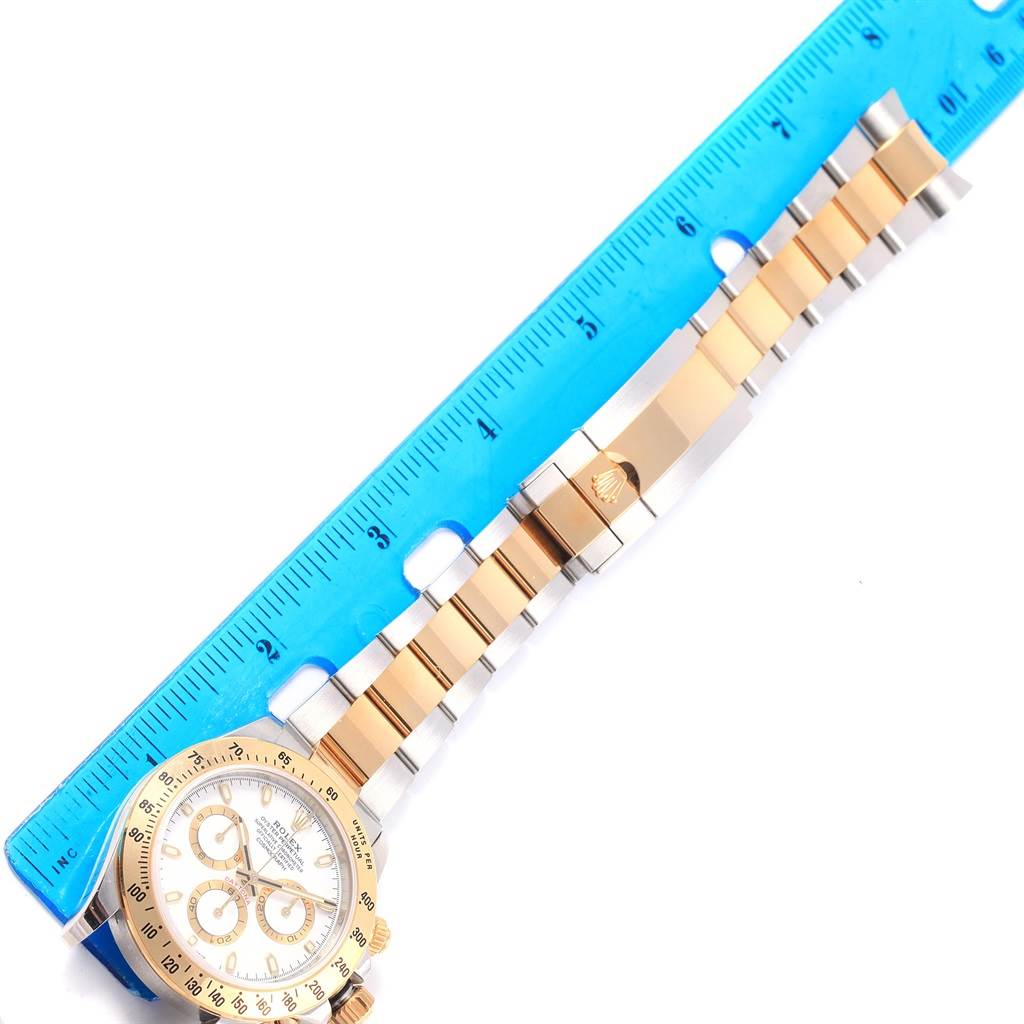 The image shows a Rolex Daytona 116503 Men's Steel and Gold (two tone) White Dial 116503 Men's Steel and Gold (two tone) White Dial watch laid flat with its bracelet alongside a blue ruler for measurement.