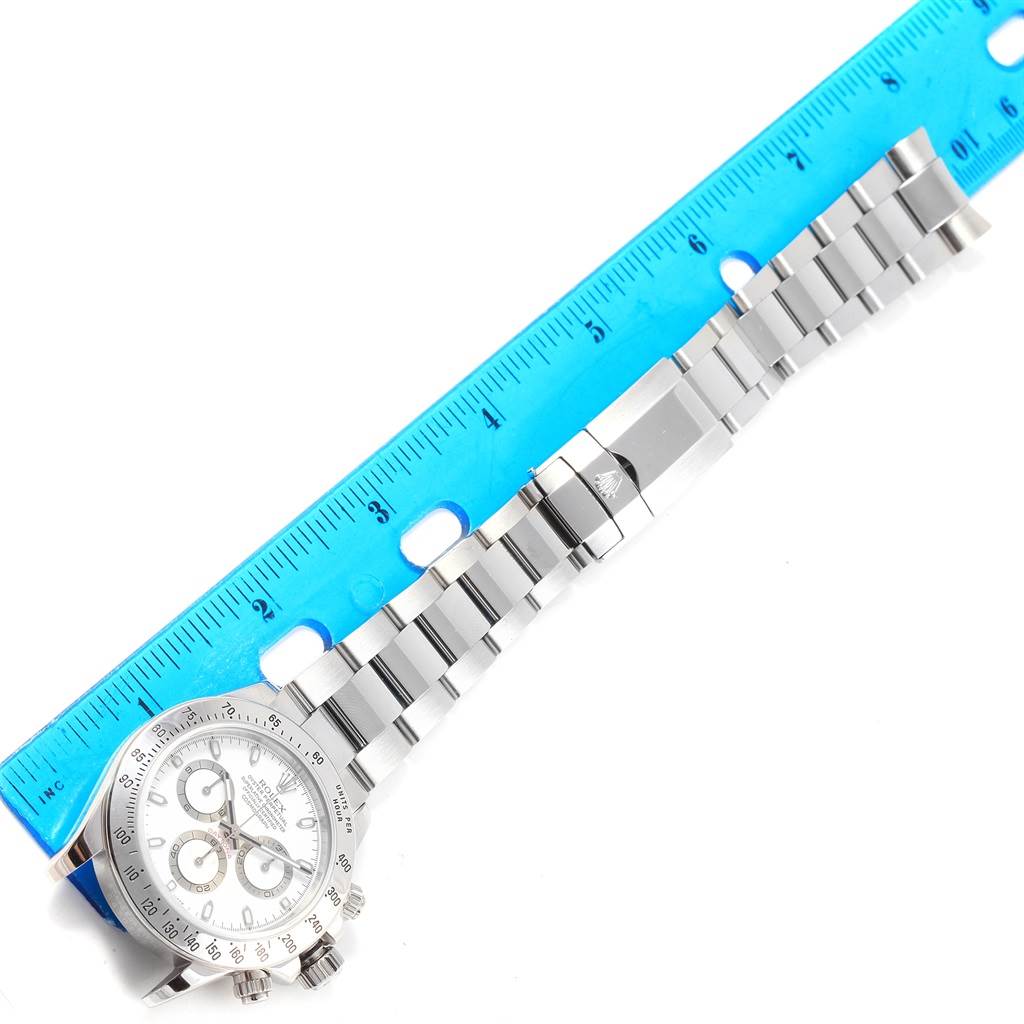 The image shows a Rolex Daytona 116520 Men's Stainless Steel White Dial 116520 Men's Stainless Steel White Dial watch lying next to a blue ruler, highlighting the bracelet and partially the watch case.