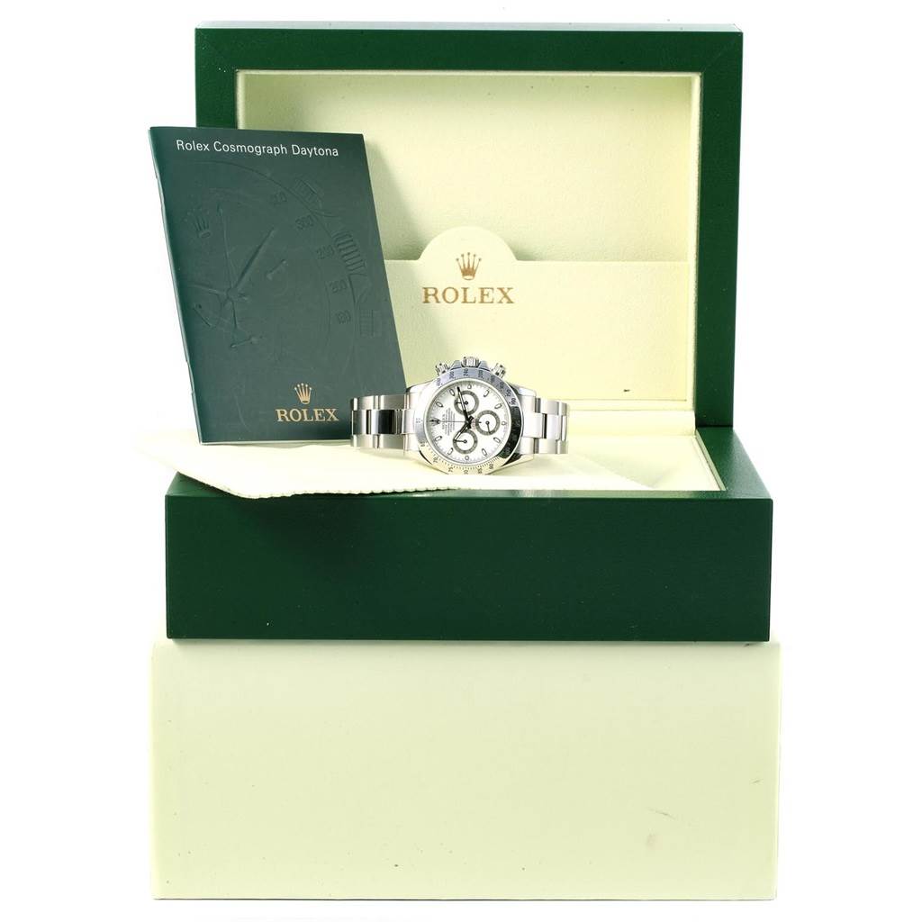 The image shows a Rolex Daytona 116520 Men's Stainless Steel White Dial 116520 Men's Stainless Steel White Dial watch, displayed in an open green and beige box, with a booklet standing inside.