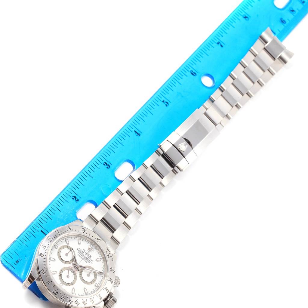 The image shows a Rolex Daytona 116520 Men's Stainless Steel White Dial 116520 Men's Stainless Steel White Dial watch laid flat with a blue ruler measuring its length.