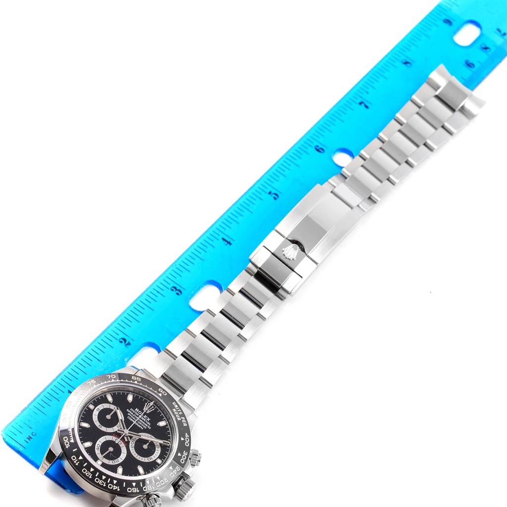 The image shows a Rolex Daytona 116500 Men's Stainless Steel Black Dial 116500 Men's Stainless Steel Black Dial watch laid flat against a ruler, displaying the face, bezel, band, and clasp.