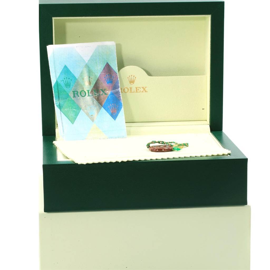 The image shows the open box of a Rolex Daytona 116528 Men's Yellow Gold Champagne Dial 116528 Men's Yellow Gold Champagne Dial watch including a booklet, a hang tag, and a cloth.