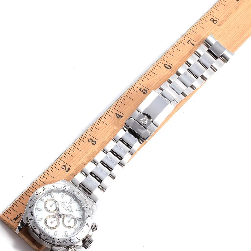 This image shows a top view of a Rolex Daytona 116520 Men's Stainless Steel White Dial 116520 Men's Stainless Steel White Dial watch laid next to a ruler.