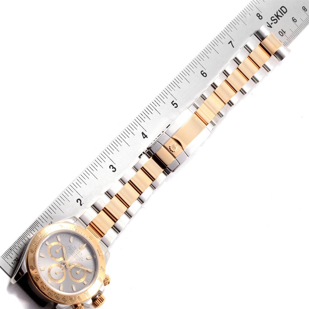 The image shows a Rolex Daytona 116523 Men's Steel and Gold (two tone) Grey Dial 116523 Men's Steel and Gold (two tone) Grey Dial watch laying flat, with a ruler measuring the length of its bracelet.