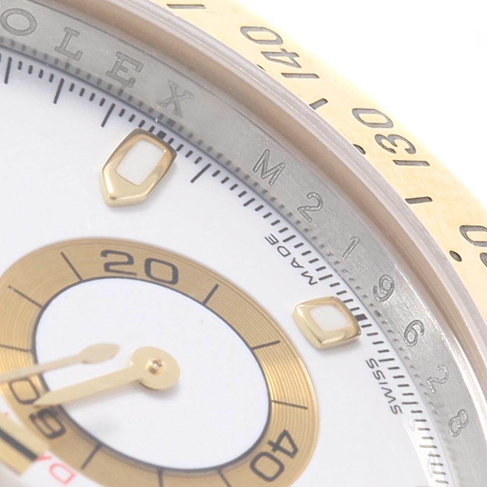 This close-up angle of the Rolex Daytona 116523 Men's Steel and Gold (two tone) White Dial 116523 Men's Steel and Gold (two tone) White Dial model showcases parts of the dial, the hand, and the edge of the bezel with markings.