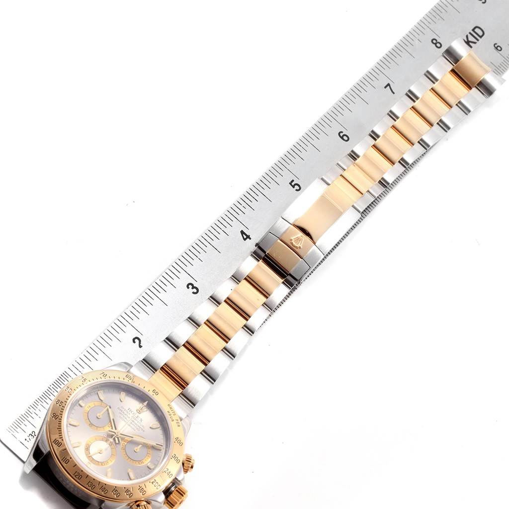 The image shows a Rolex Daytona 116523 Men's Steel and Gold (two tone) Grey Dial 116523 Men's Steel and Gold (two tone) Grey Dial watch chain and dial, placed next to a ruler for measurement.