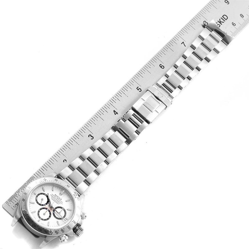 The image shows a top view of a Rolex Daytona watch, displaying its face, bracelet, and clasp alongside a ruler for scale.