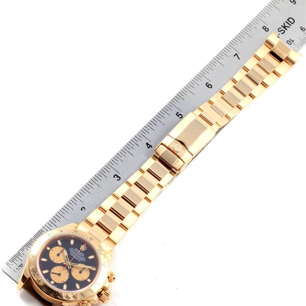 The image shows a Rolex Daytona 116528 Men's Yellow Gold Black Dial 116528 Men's Yellow Gold Black Dial watch from an overhead angle with its dial and bracelet visible, next to a ruler.