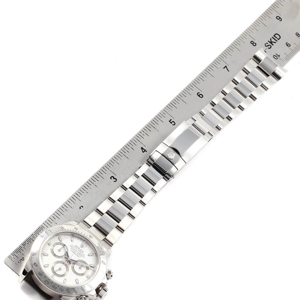 The image displays a Rolex Daytona 116520 Men's Stainless Steel White Dial 116520 Men's Stainless Steel White Dial watch laid flat alongside a ruler, showing the face and bracelet.