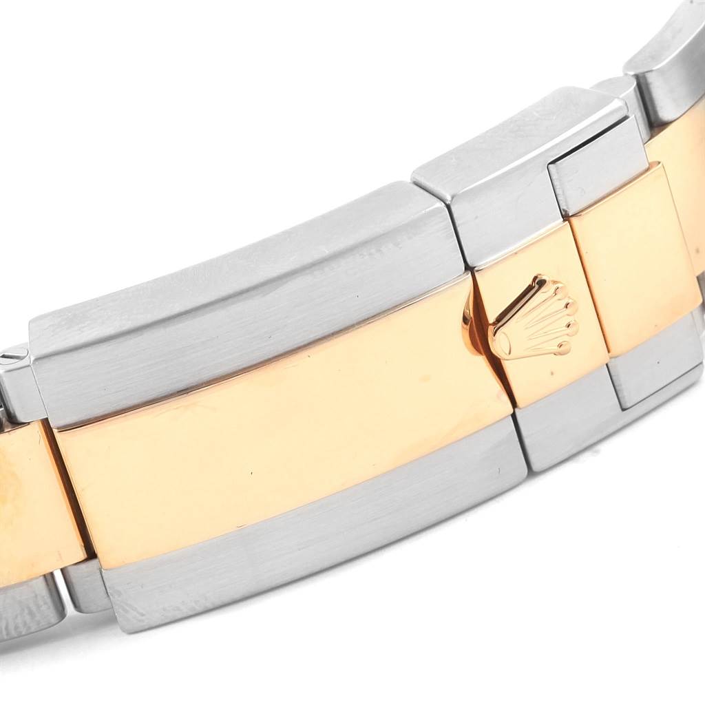 The image shows a close-up of the bracelet and clasp of a Rolex Daytona 116523 Men's Steel and Gold (two tone) Black Dial 116523 Men's Steel and Gold (two tone) Black Dial watch, featuring two-tone metal with the Rolex crown logo.