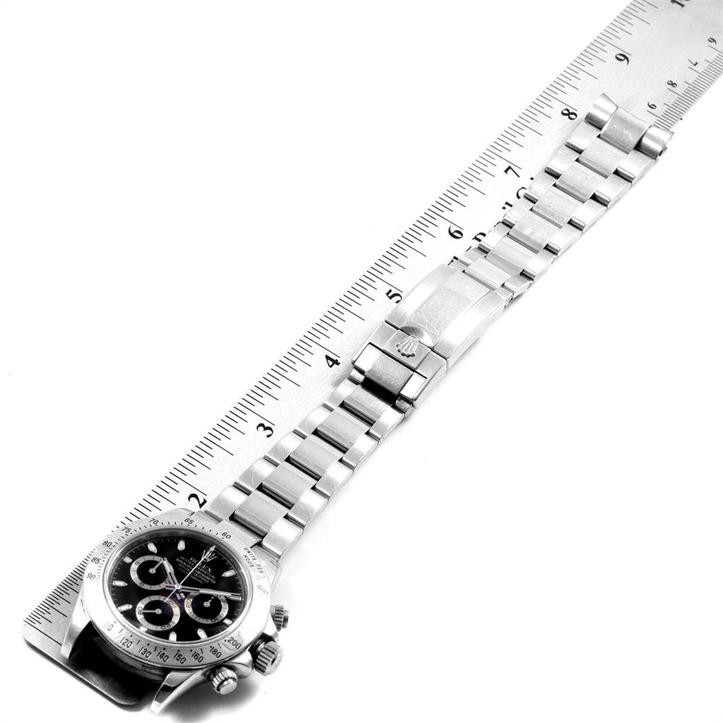 The image displays a Rolex Daytona 116520 Men's Stainless Steel Black Dial 116520 Men's Stainless Steel Black Dial watch laid flat next to a ruler, showing its face and entire bracelet.