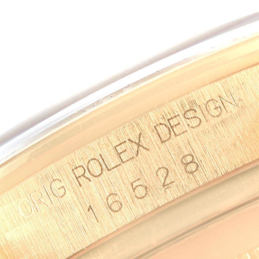 The image shows a close-up of the engraved bezel on a Rolex Daytona 16528 Men's Yellow Gold Black Dial 16528 Men's Yellow Gold Black Dial watch displaying the model number 16528 and "Rolex Design."