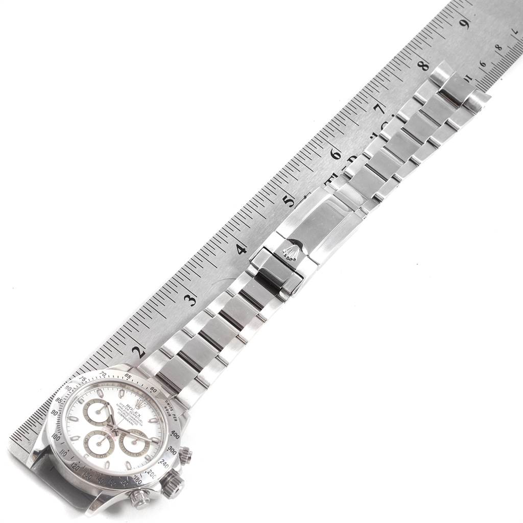 The image shows a top view of a Rolex Daytona 116520 Men's Stainless Steel White Dial 116520 Men's Stainless Steel White Dial watch, displaying the face and the entire metal bracelet beside a ruler for measurement.