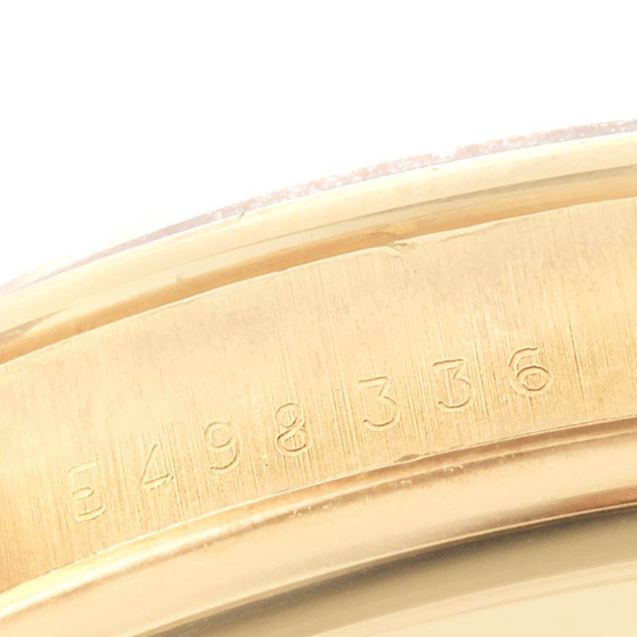This close-up image of a Rolex Daytona 16528 Men's Yellow Gold Black Dial 16528 Men's Yellow Gold Black Dial watch shows the engraved serial number on its gold casing at an angled view.