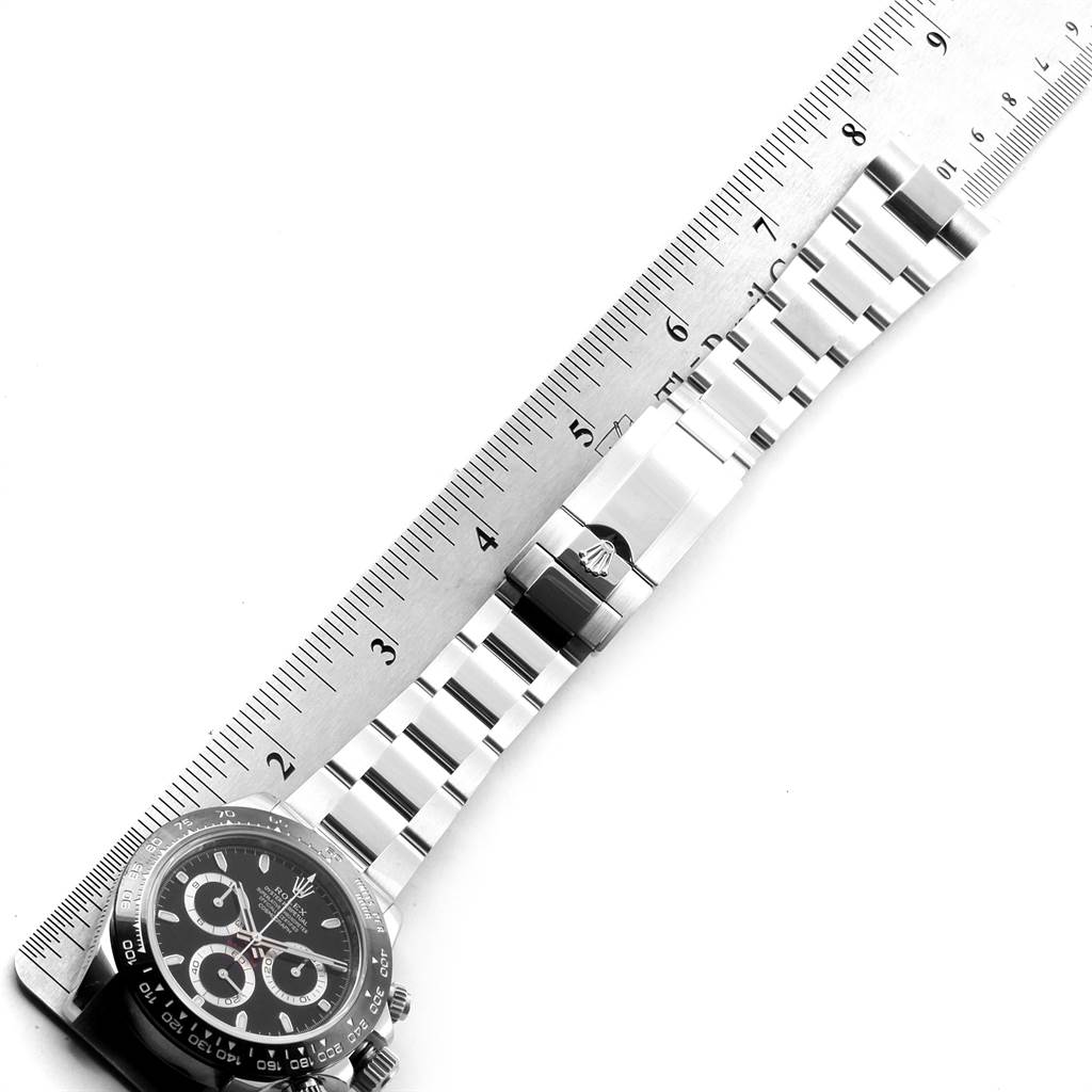 The image shows the side view of a Rolex Daytona 116500 Men's Stainless Steel Black Dial 116500 Men's Stainless Steel Black Dial watch face and bracelet, positioned adjacent to a ruler.