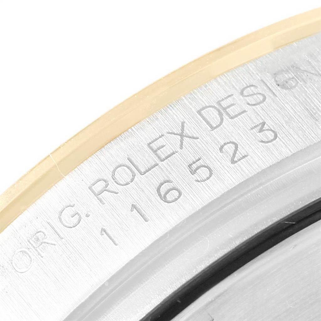 The image shows a close-up of the engraved bezel and serial number of a Rolex Daytona 116523 Men
s Steel and Gold (two tone) Black Dial 116523 Men
s Steel and Gold (two tone) Black Dial watch.