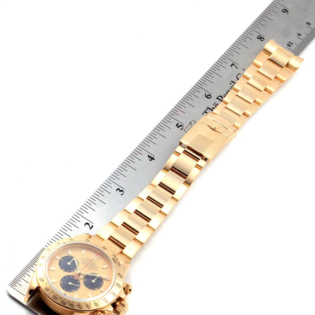 The Rolex Daytona 116528 Men's Yellow Gold Champagne Dial 116528 Men's Yellow Gold Champagne Dial watch is shown from a top angle, displaying the face, bezel, and bracelet alongside a ruler for size reference.