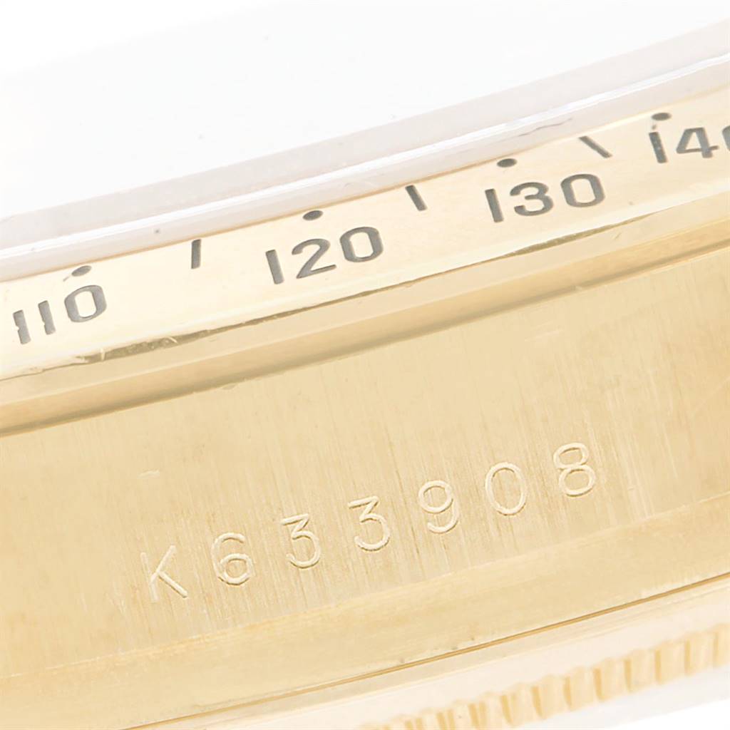This close-up image shows the side of a Rolex Daytona 116528 Men's Yellow Gold Black Dial 116528 Men's Yellow Gold Black Dial watch, revealing a portion of the bezel with tachymeter scale and a serial number.