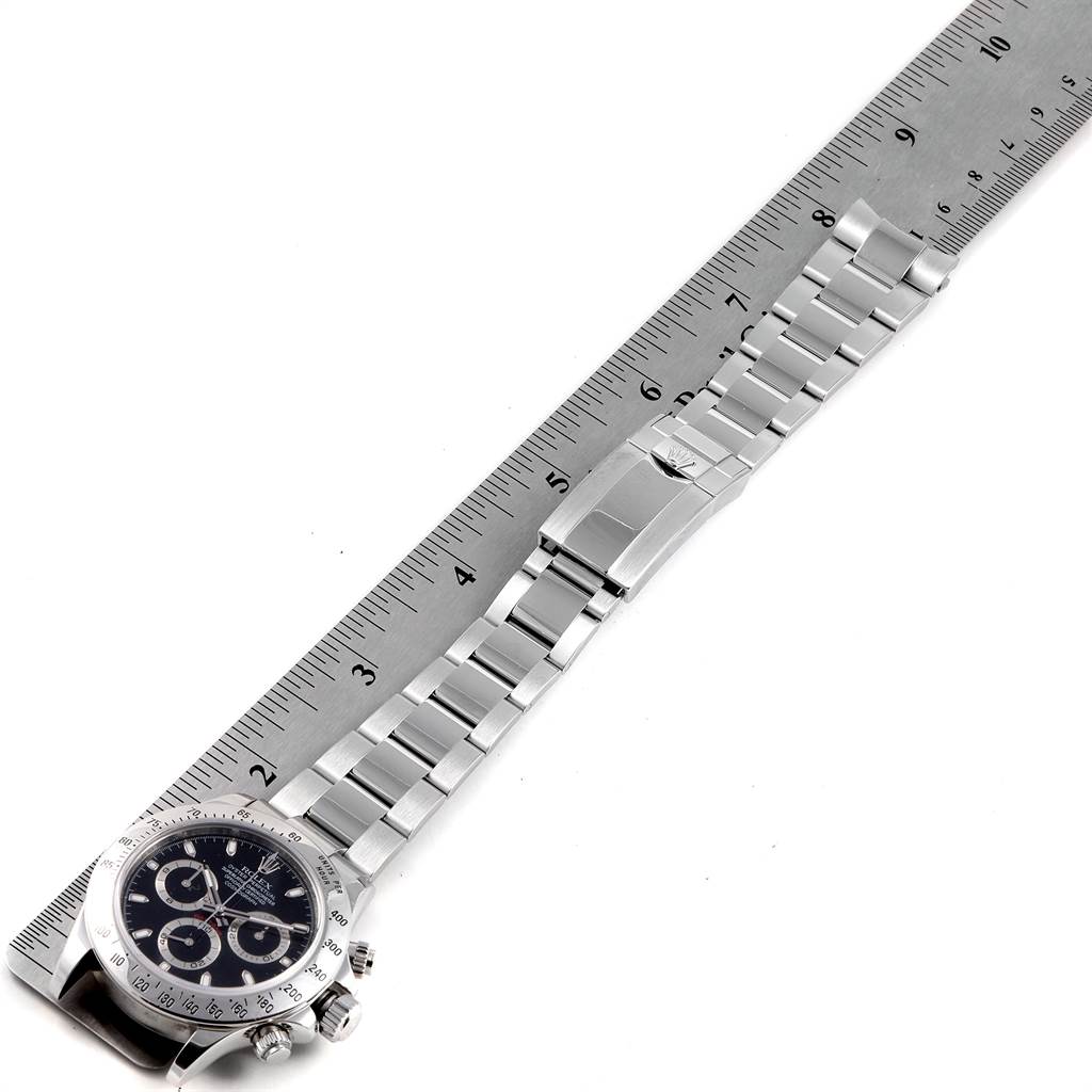 The image shows a Rolex Daytona 116520 Men's Stainless Steel Black Dial 116520 Men's Stainless Steel Black Dial watch laid flat, with the bracelet placed against a ruler for measurement.