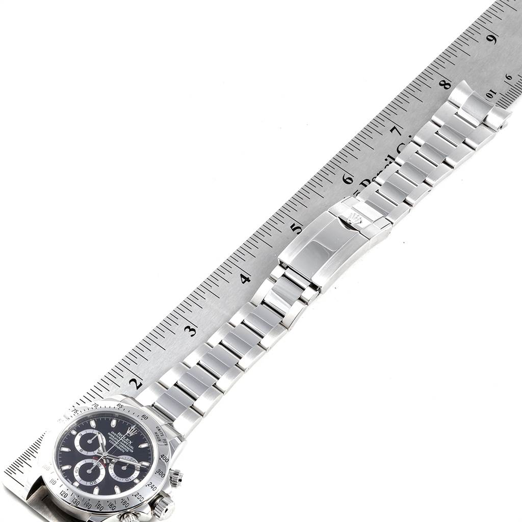 The image shows a Rolex Daytona 116520 Men's Stainless Steel Black Dial 116520 Men's Stainless Steel Black Dial watch positioned alongside a ruler, highlighting its full bracelet and clasp.