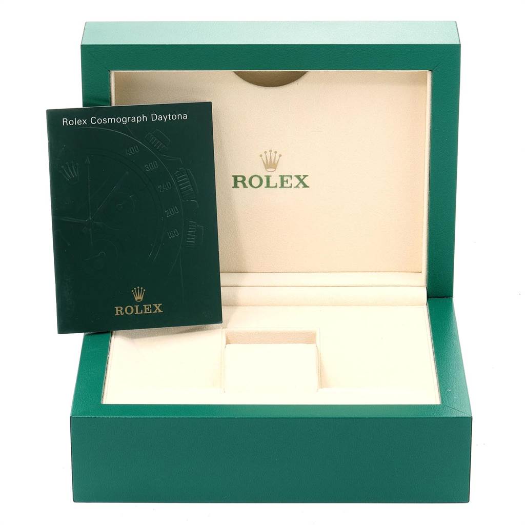 The image shows an open green Rolex box with a Rolex Cosmograph Daytona manual propped inside it.