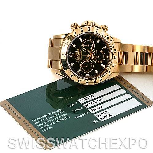 The Rolex Daytona 116528 Men's Yellow Gold Black Dial 116528 Men's Yellow Gold Black Dial watch is shown at a slight angle, displaying its face and bracelet, atop a warranty card.