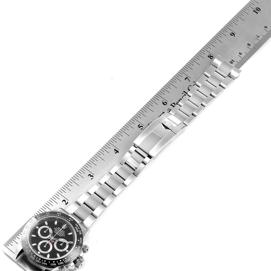 The image shows a Rolex Daytona 116500 Men's Stainless Steel Black Dial 116500 Men's Stainless Steel Black Dial watch, viewed from above, with a metal bracelet and clasp alongside a ruler for measurement.