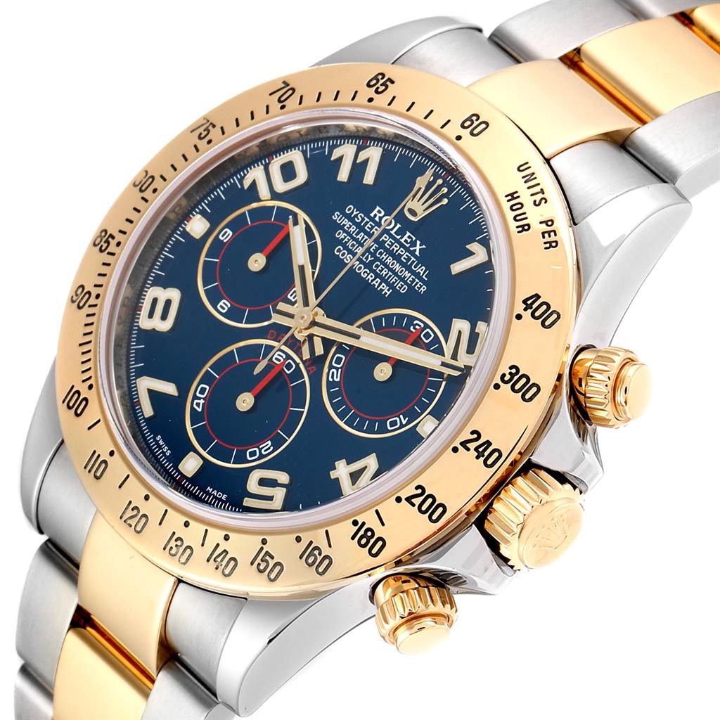 The angled close-up of the Rolex Daytona 116523 Men's Steel and Gold (two tone) Blue Dial 116523 Men's Steel and Gold (two tone) Blue Dial watch shows the face, bezel, and crown, with a clear view of the chronograph dials.
