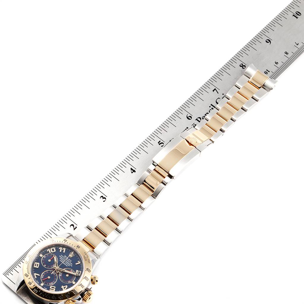 This image shows a partially extended Rolex Daytona 116523 Men's Steel and Gold (two tone) Blue Dial 116523 Men's Steel and Gold (two tone) Blue Dial watch laid out next to a ruler, highlighting the bracelet and watch face.