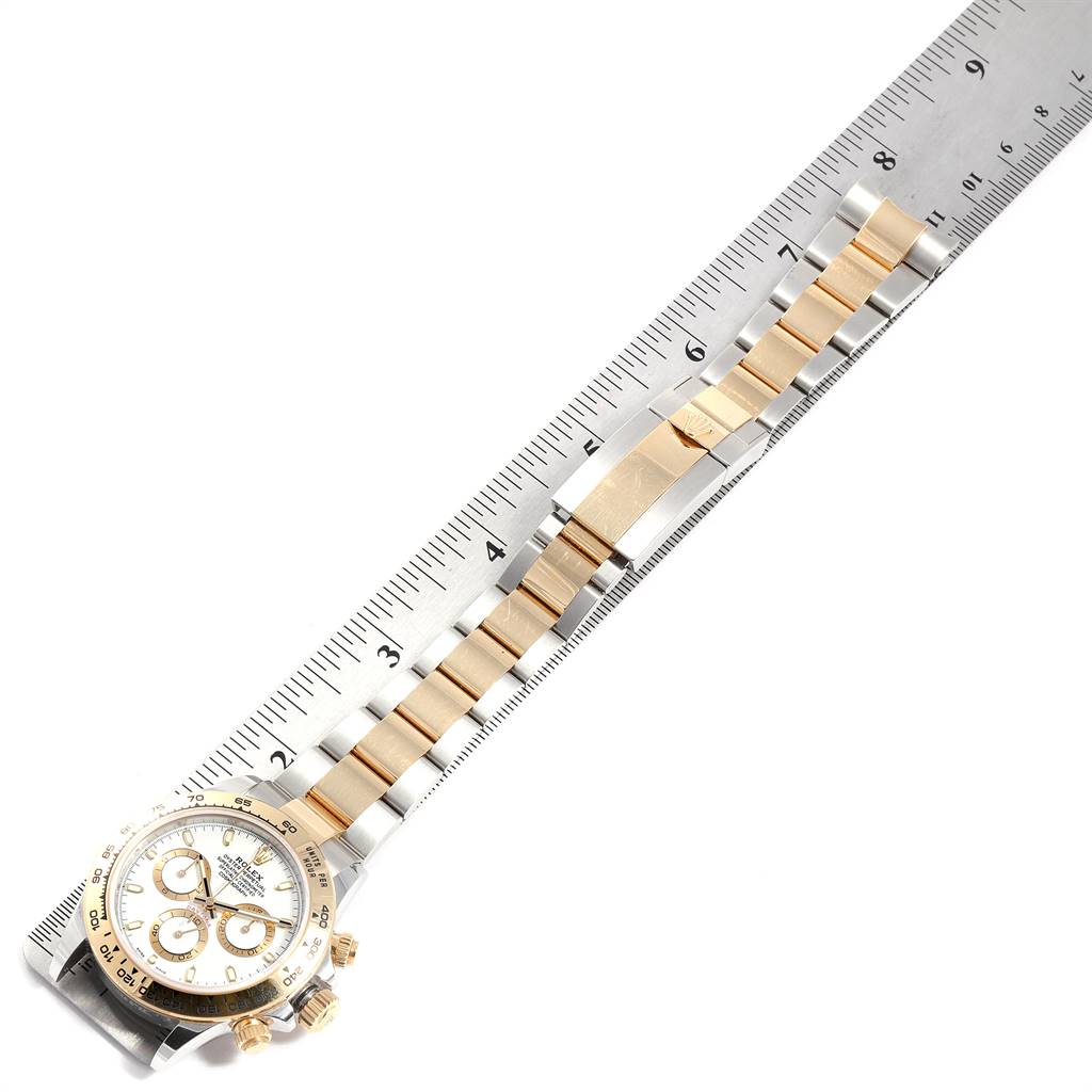 The image shows a Rolex Daytona 116503 Men's Steel and Gold (two tone) White Dial 116503 Men's Steel and Gold (two tone) White Dial watch with a gold and silver link bracelet and clasp laid next to a ruler.