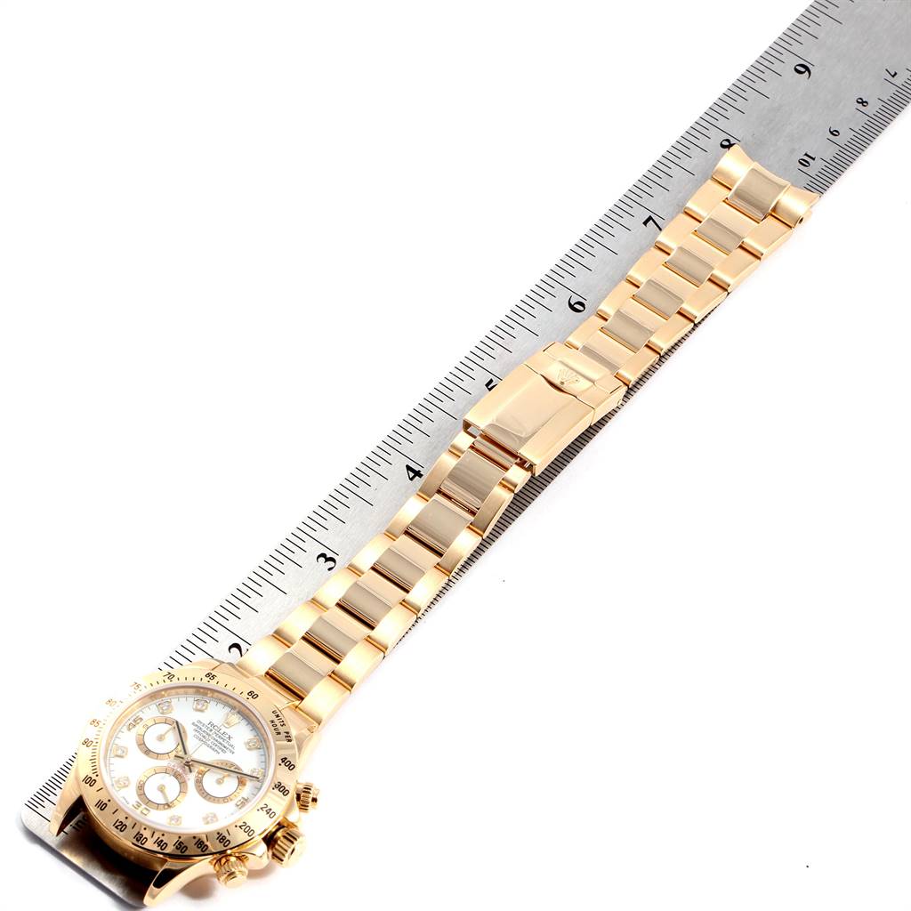 The image shows a top-down view of a Rolex Daytona 116528 Men's Yellow Gold White Dial 116528 Men's Yellow Gold White Dial watch, highlighting its gold bracelet and clasp alongside a measuring ruler.