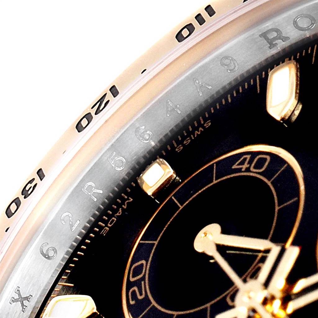 This close-up of the Rolex Daytona 116523 Men
s Steel and Gold (two tone) Black Dial 116523 Men
s Steel and Gold (two tone) Black Dial watch shows a portion of the bezel and the dial with intricate markings.
