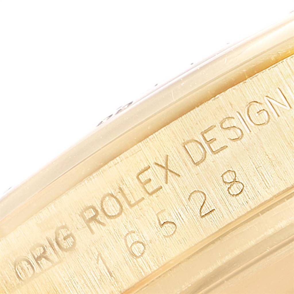 Close-up view of the side of a Rolex Daytona 16528 Men
s Yellow Gold Champagne Dial 16528 Men
s Yellow Gold Champagne Dial watch, showing the engraved model number and "ROLEX DESIGN."