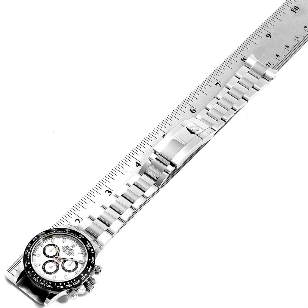 The image shows a top-down view of a Rolex Daytona 116500 Men's Stainless Steel White Dial 116500 Men's Stainless Steel White Dial watch, including its face and bracelet, alongside a measurement ruler.