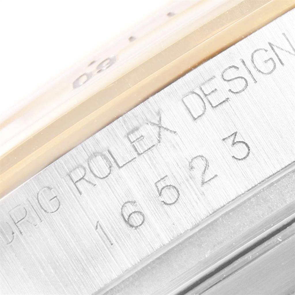 The image shows a close-up of the side of a Rolex Daytona 16523 Men's Steel and Gold (two tone) White Dial 16523 Men's Steel and Gold (two tone) White Dial watch, featuring the engraved model number and text "ROLEX DESIGN."