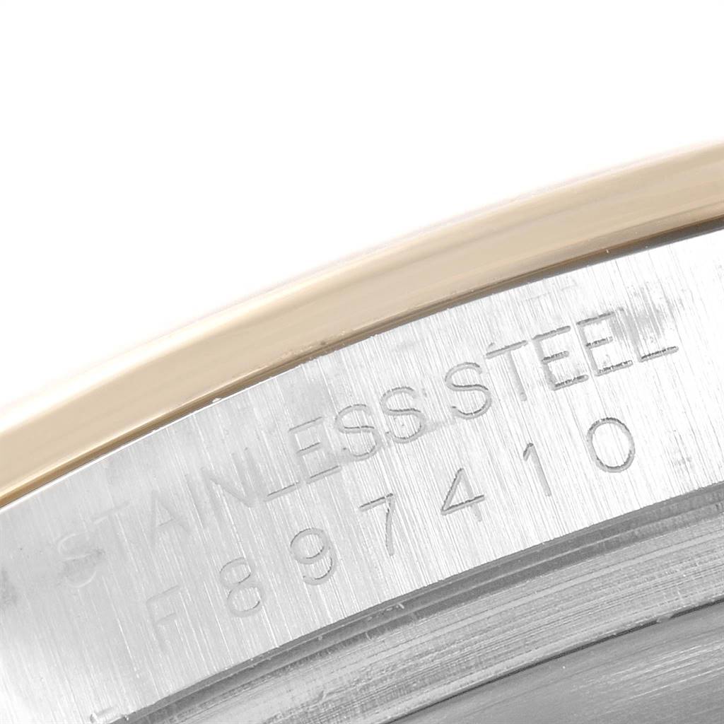 This image shows a close-up of the etched serial number and "STAINLESS STEEL" text on a Rolex Daytona 116523 Men's Steel and Gold (two tone) Black Dial 116523 Men's Steel and Gold (two tone) Black Dial watch bezel.