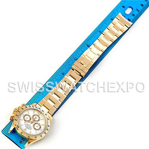 The Rolex Daytona 16528 Men's Yellow Gold White Dial 16528 Men's Yellow Gold White Dial watch is shown from a top-down angle, featuring its full gold bracelet placed next to a blue ruler for scale.