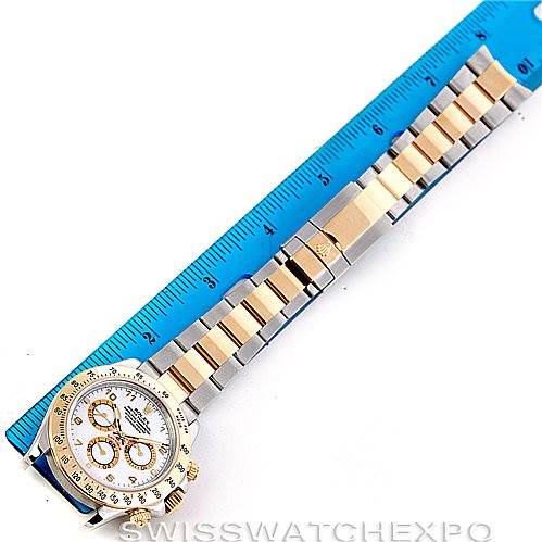 The Rolex Daytona 116523 Men's Steel and Gold (two tone) White Dial 116523 Men's Steel and Gold (two tone) White Dial watch is shown from a top view, featuring its face, bezel, and bracelet alongside a ruler for scale.